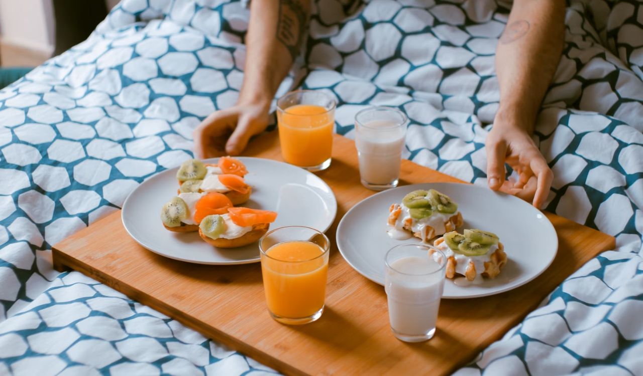 Person holding food on wooden tray
