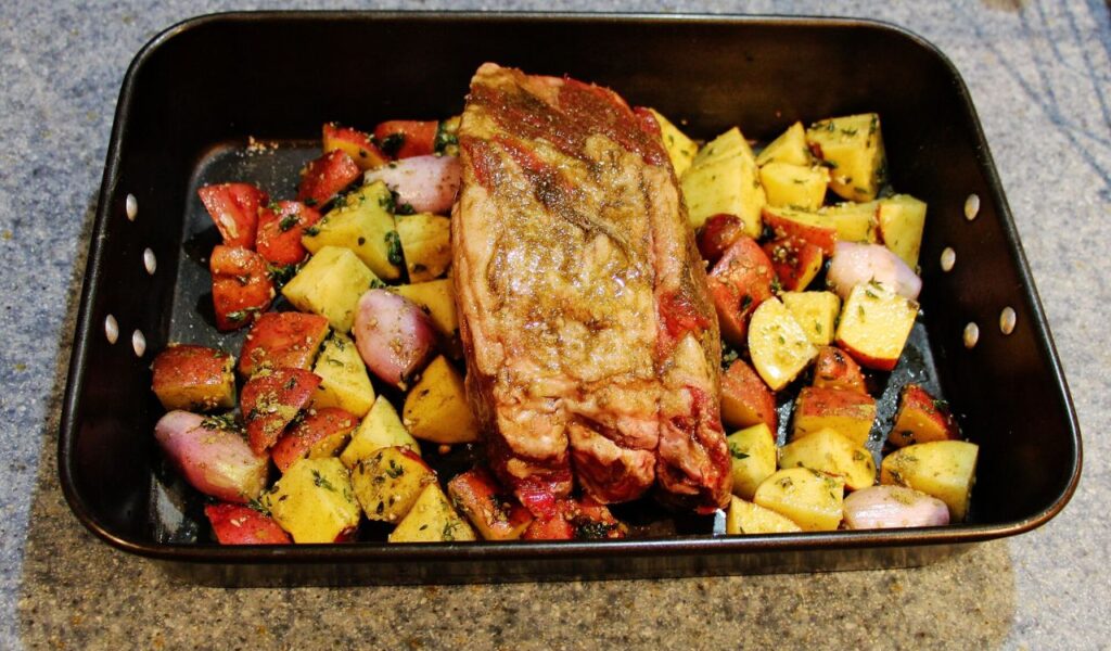 Prime rib with potatoes and spices in baking tray