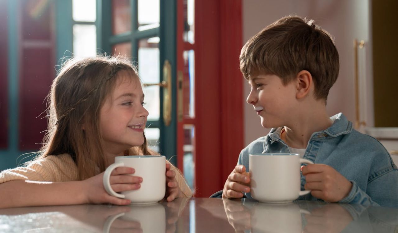 Two kids drinking milk from mug