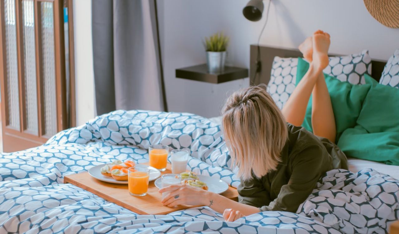 Woman lying on bed with breakfast tray