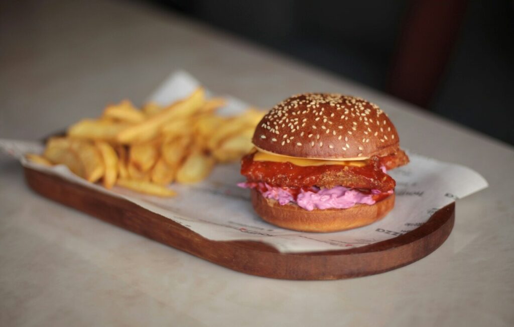 A gourmet burger with fancy toppings but noticeably smaller than a standard burger