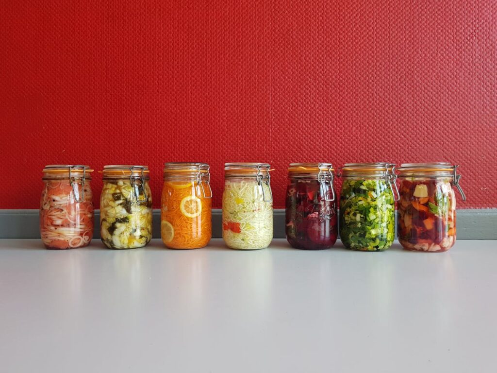 A bright pantry shelf lined with colorful jars filled with pickled vegetables, creating a vibrant mosaic of colors.