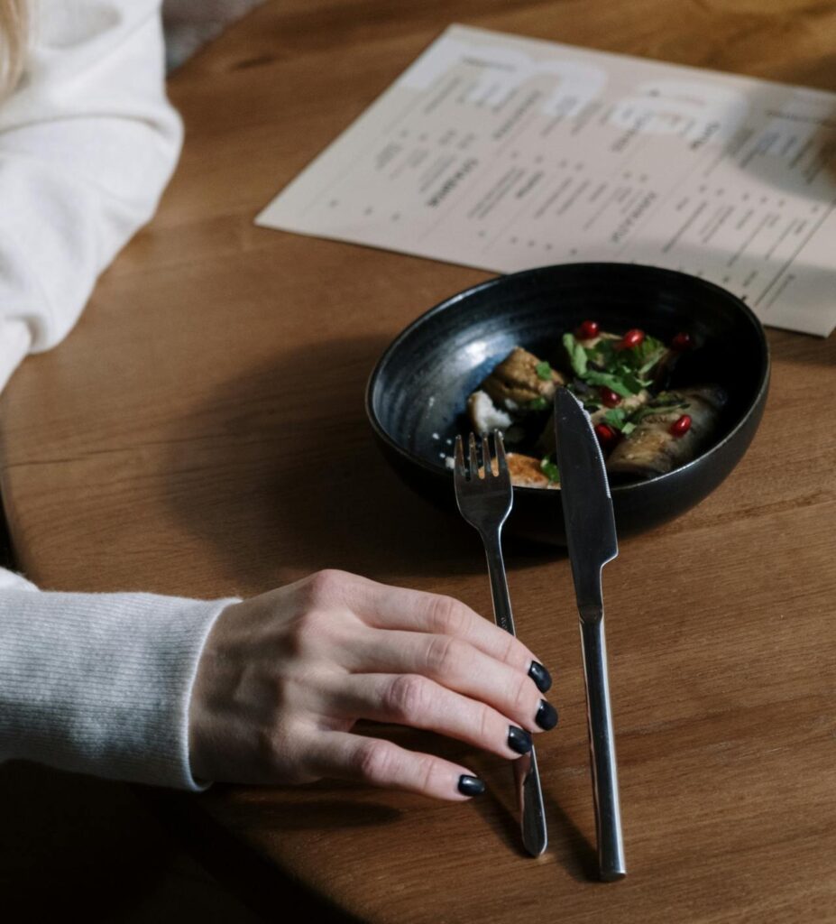 Close-up of Woman Sitting at the Table with a Meal in front of Her