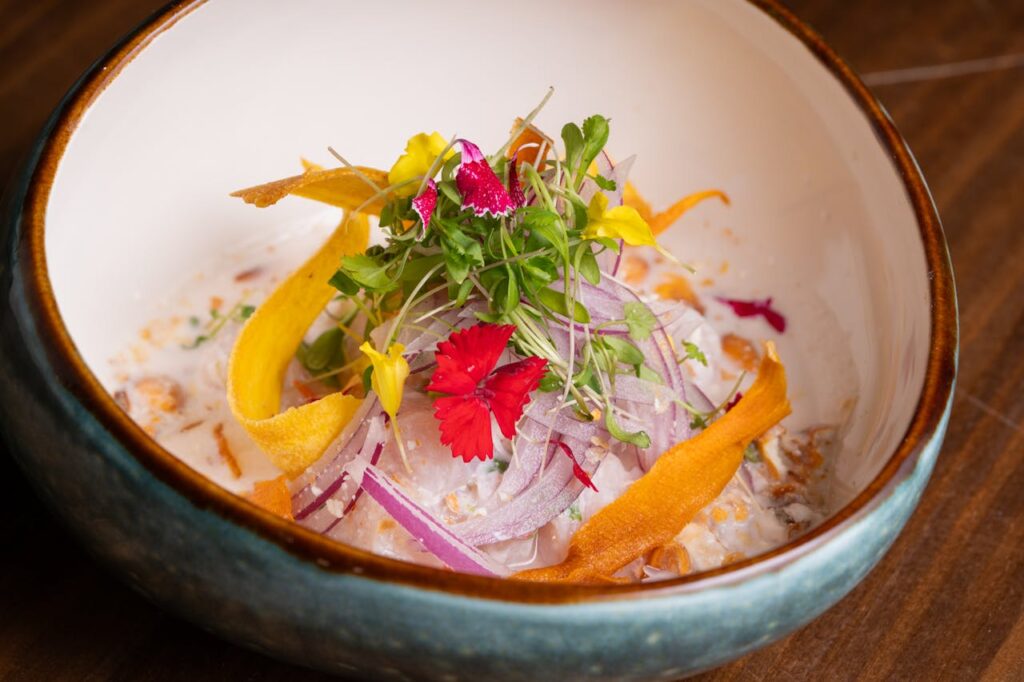 A delicate salad with microgreens, edible flowers, and a light drizzle of dressing on a large plate.