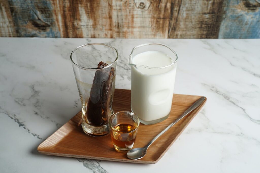 A glass of coffee milk with a spoon resting beside it.