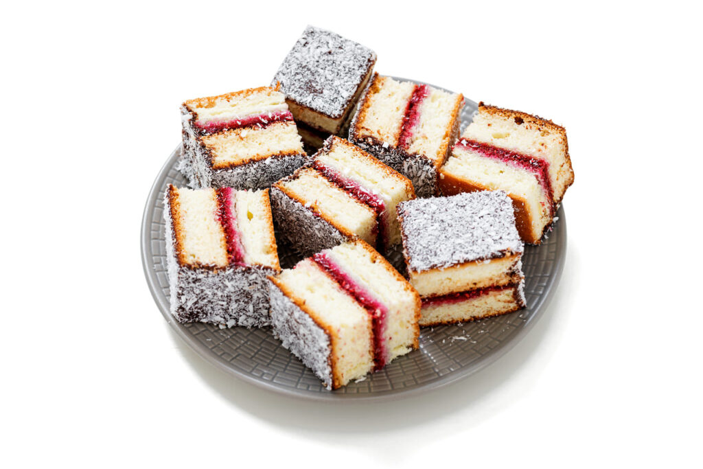 Australian lamington cake with  raspberry jam and chocolate sauce sprinkled with coconut flakes.isolated on white background