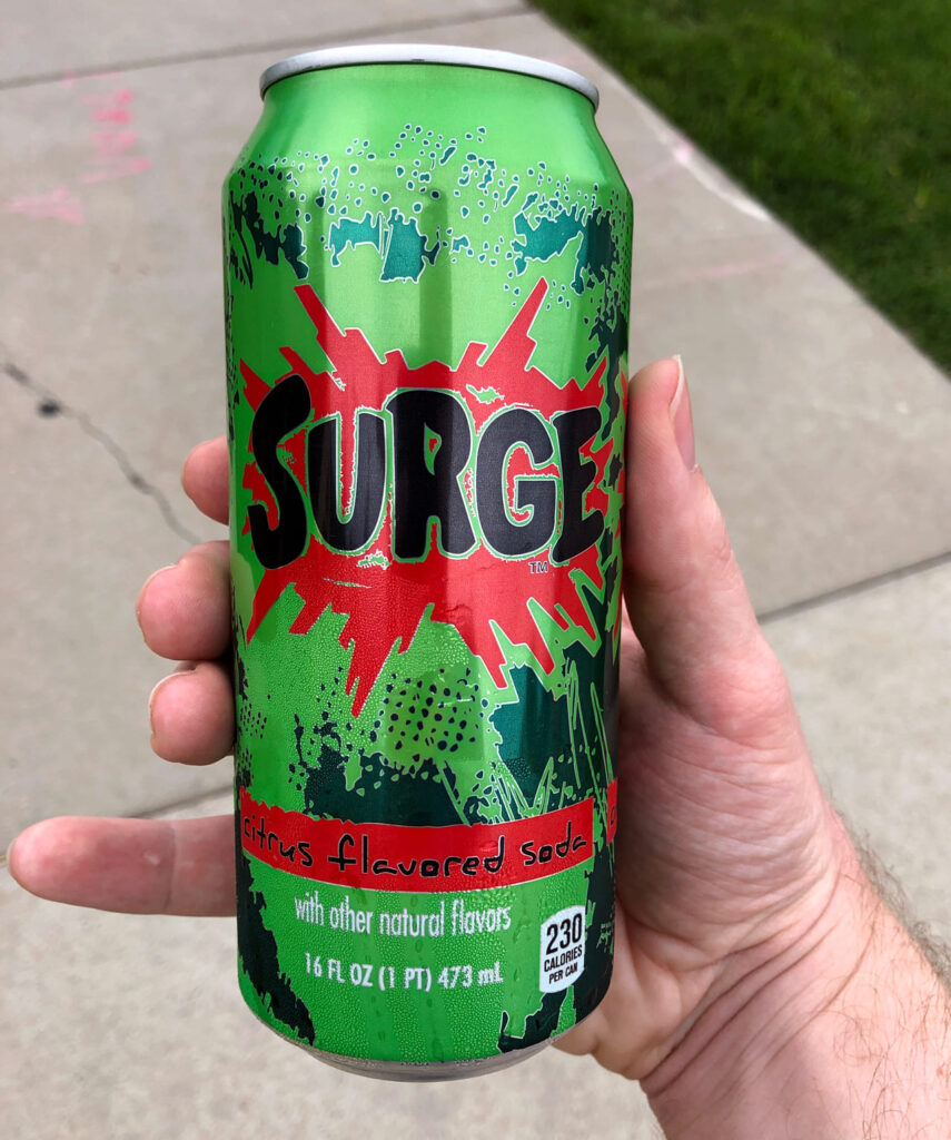 Surge soda can being enjoyed by someone outdoors.
