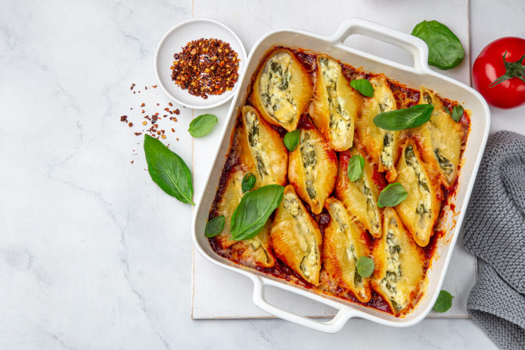 Ricotta and spinach stuffed shell  pasta with tomato sauce in white baking dish, white background, top view