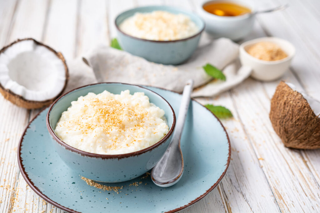Sweet and creamy coconut rice pudding with honey, topped with grated and toasted coconut in a ceramic bowl