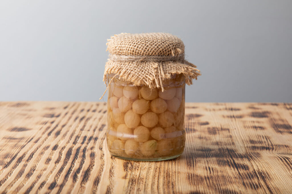 Pickled pearl onions in a glass jar with linen material on top