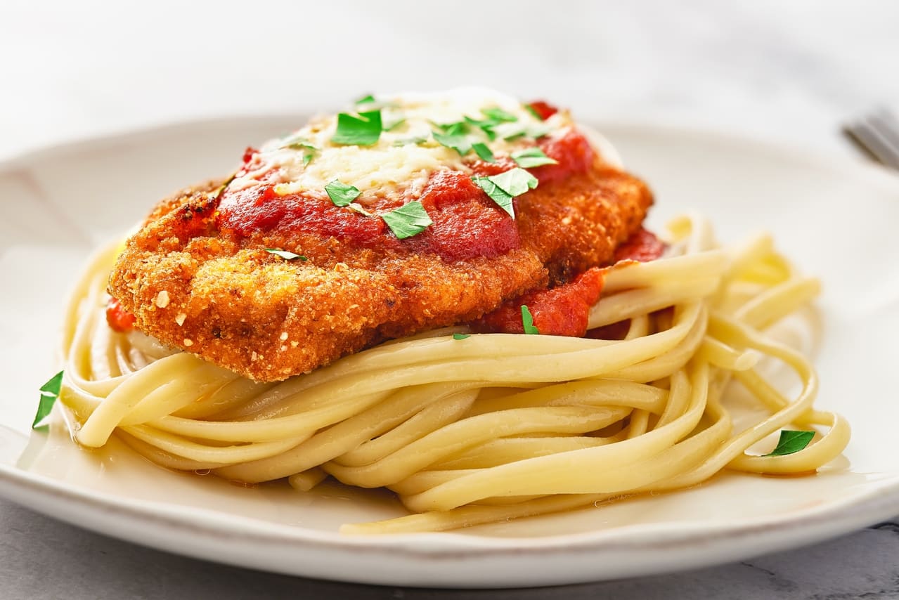 Close up Chicken Parmesan and spaghetti in a plate. Low angle view. Macro shot with focus stacking.