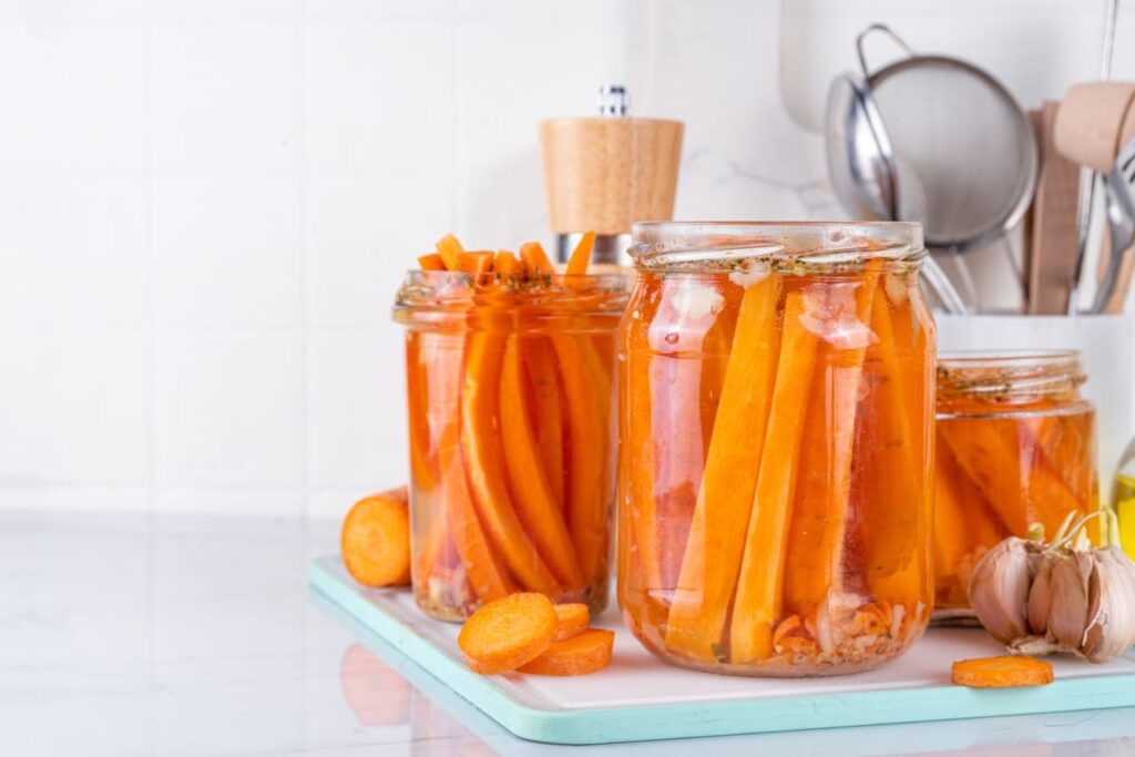 Homemade pickled carrots, Fermented carrot, salted conserved preserved vegetables canned in glass jars on kitchen table