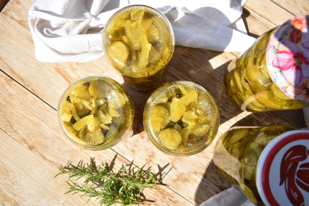 cucumber pickles in jars upside down on wooden background, top view