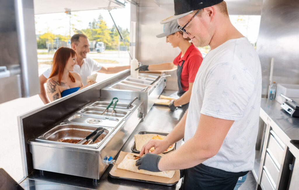 Young chefs in a food truck preparing Mexican food for their waiting customers