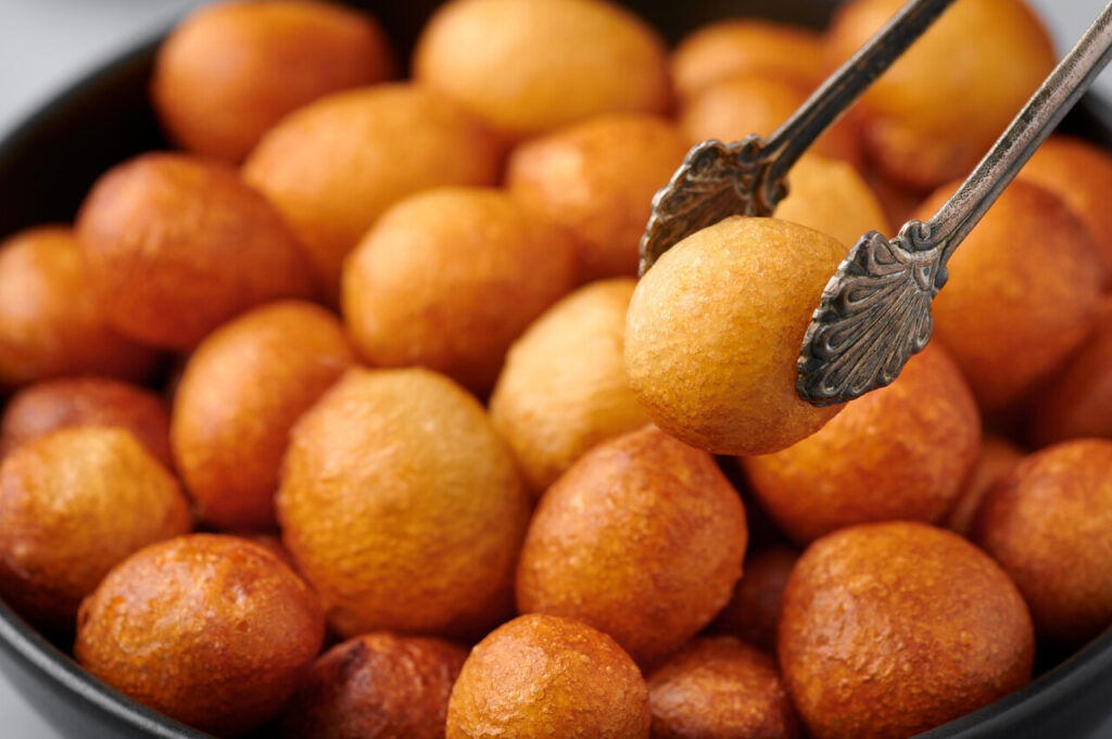 Loukoumades or luqaimat or lokma in black bowl. Loukoumades is an eastern cuisine donunts popular during Ramazan.