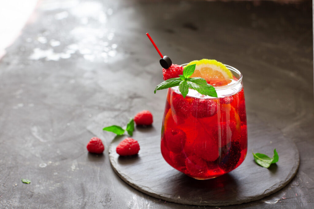 Sparkling pink raspberry lemonade on dark background, summer refreshing drink