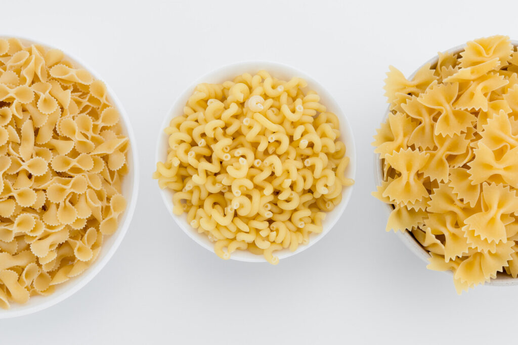 Top view of three types of small raw macaroni in plates