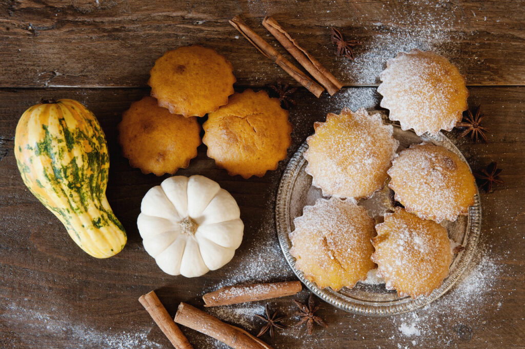 Homemade delicious pastry muffin with decorative pumpkin and cinnamon on wooden background
