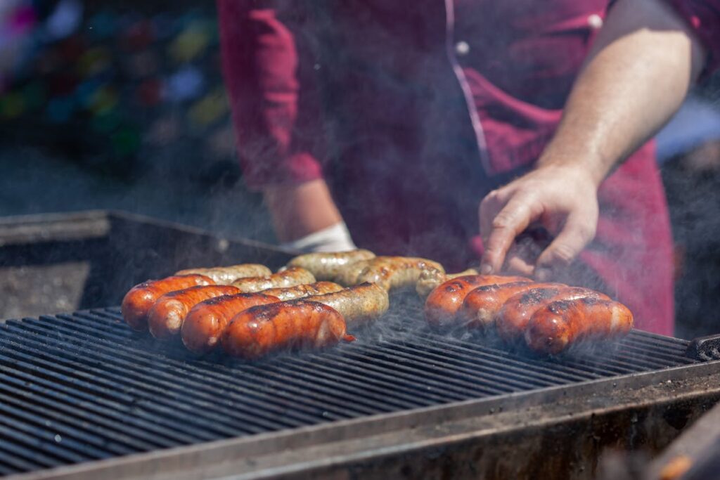 A pitmaster brushing sauce on brisket with bottles of Louisiana hot sauce nearby.