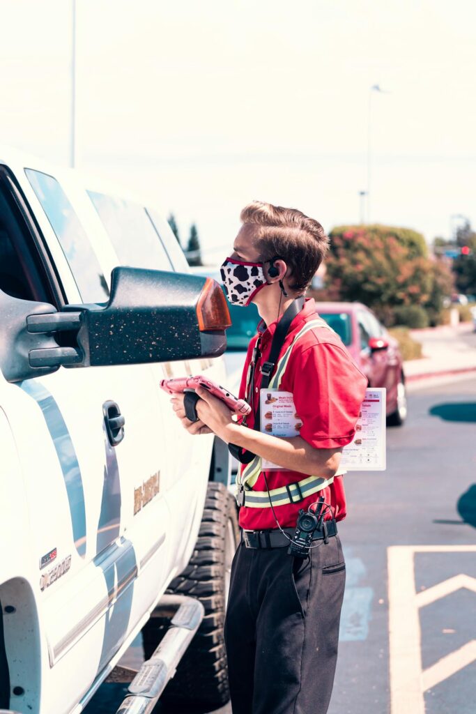 Worker handing food to a parked car near drive-thru
