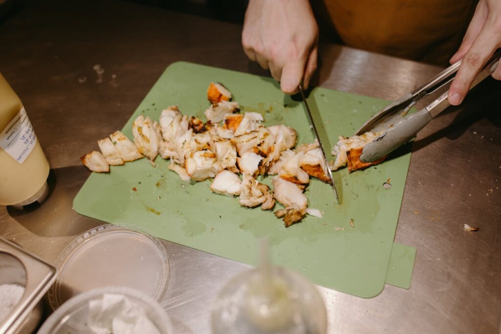 Worker placing grilled chicken pieces on a sandwich line.