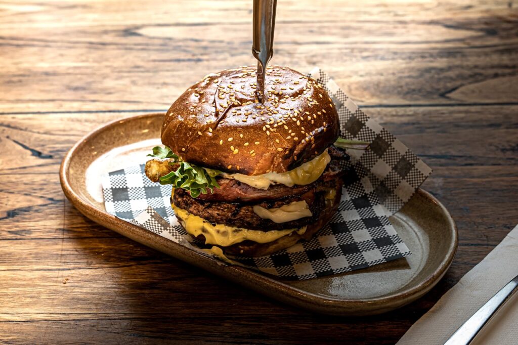 A neatly layered burger on a wooden board, showcasing a harmonious blend of ingredients.