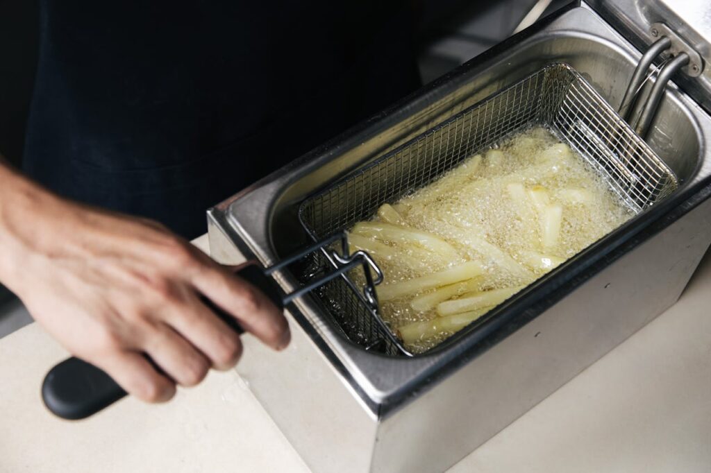 Basket of French fries cooking in deep fryer.