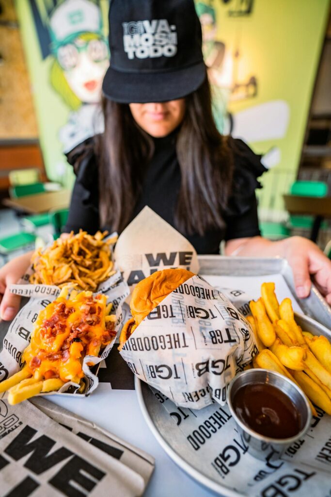 Fast food employee serving tray with burgers and fries.