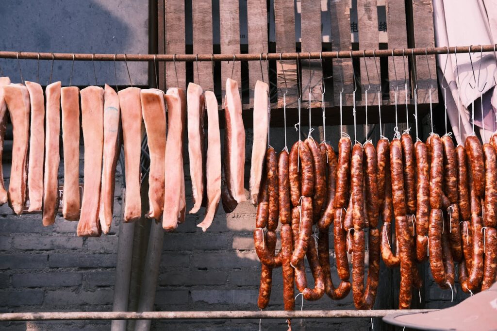 Smoked sausages hanging in a Texas smokehouse with a rich red spice rub.