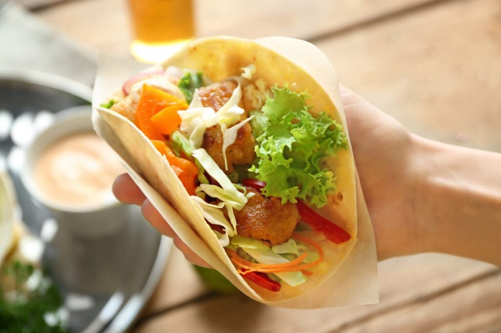 Hand of woman holding delicious fish taco, closeup