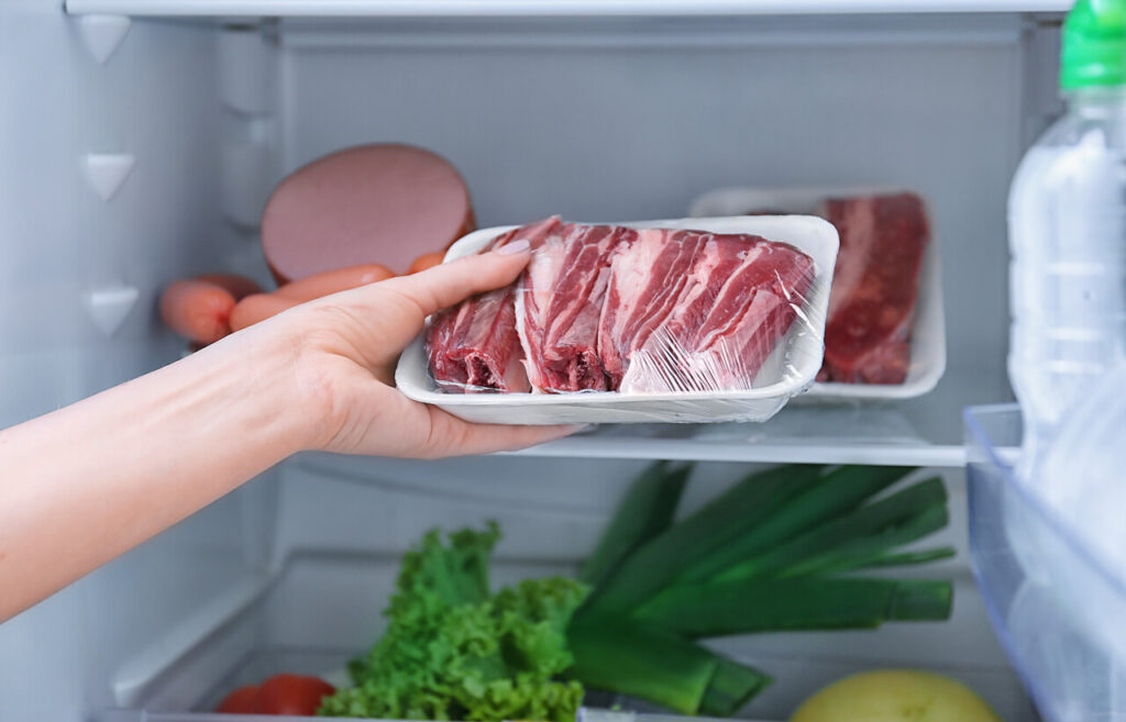 Packaged meat placed on the lower shelf of a fridge