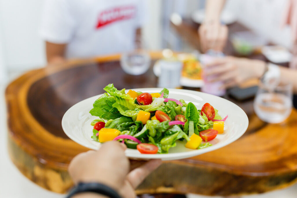 Waiter serving fresh vegetable salad in restaurant