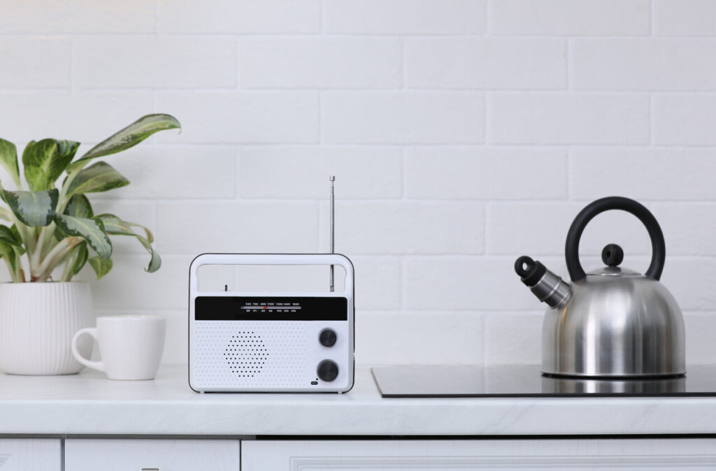 Stylish radio on kitchen counter near white brick wall