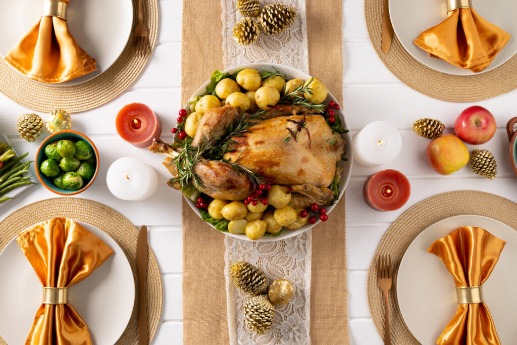 Overhead view of thanksgiving table with roast turkey, vegetables and autumn decoration on wood. Thanksgiving, autumn, fall, american tradition and celebration concept.