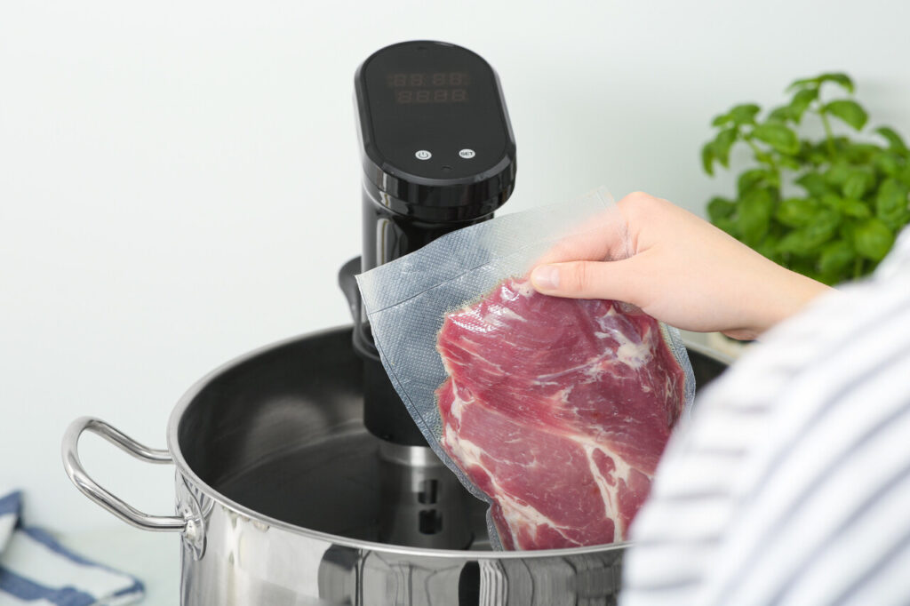 A bowl or pot filled with cold water holding sealed meat,