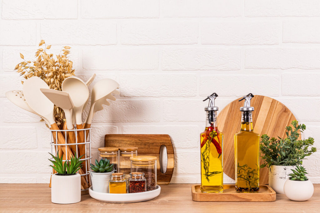 A small tray holding olive oil bottles and spice jars beside a stove.