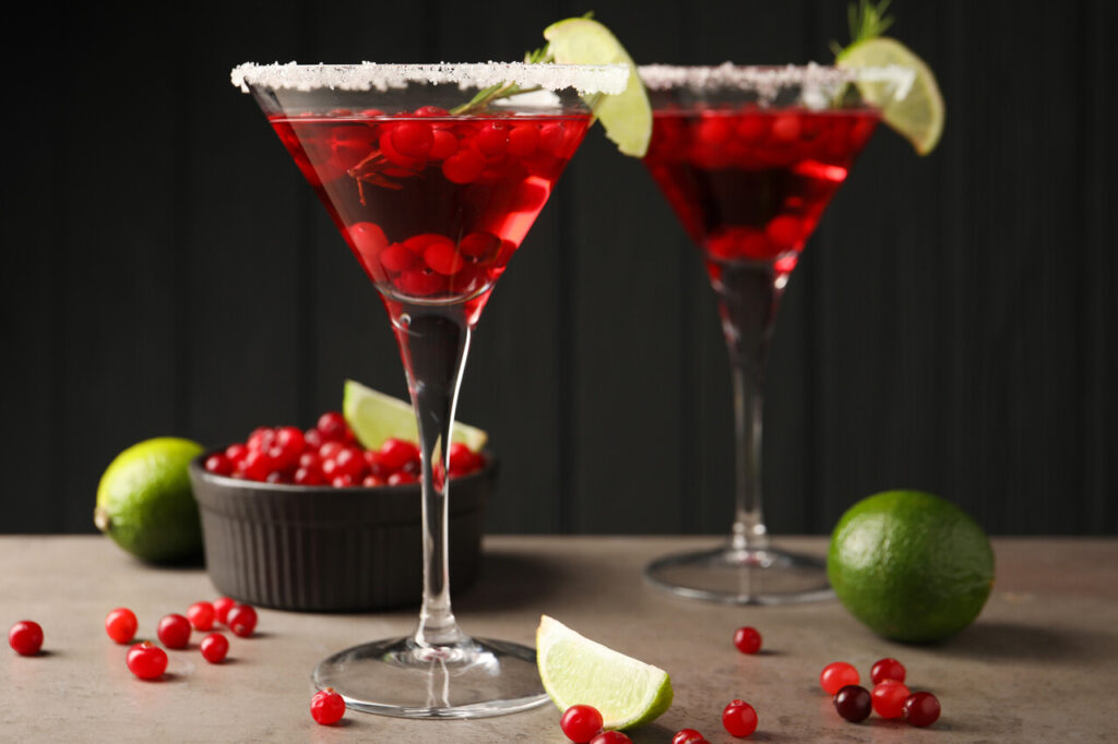 A close-up of a cranberry martini with fresh cranberries