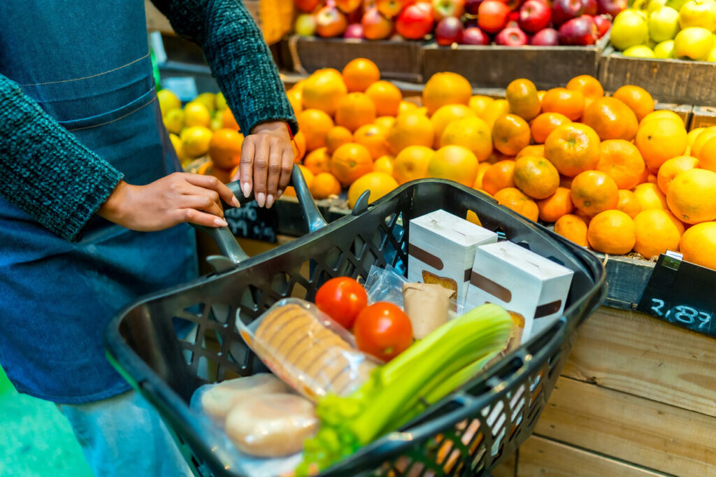 a shopping cart full of fresh produce, packaged goods, and vegetables in a health food store