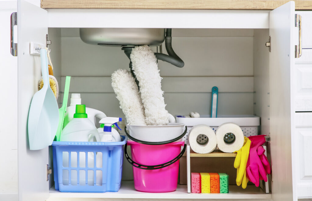 A cleaning caddy holding sprays, cloths, and brushes stored neatly under the sink.