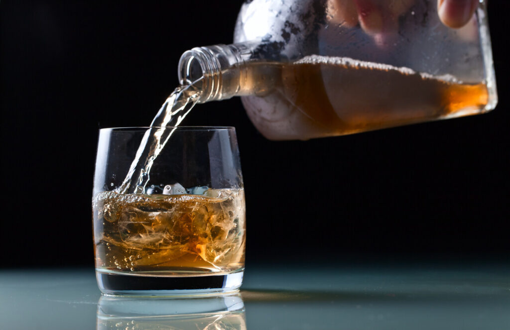 Bartender pouring a whiskey neat into a glass.