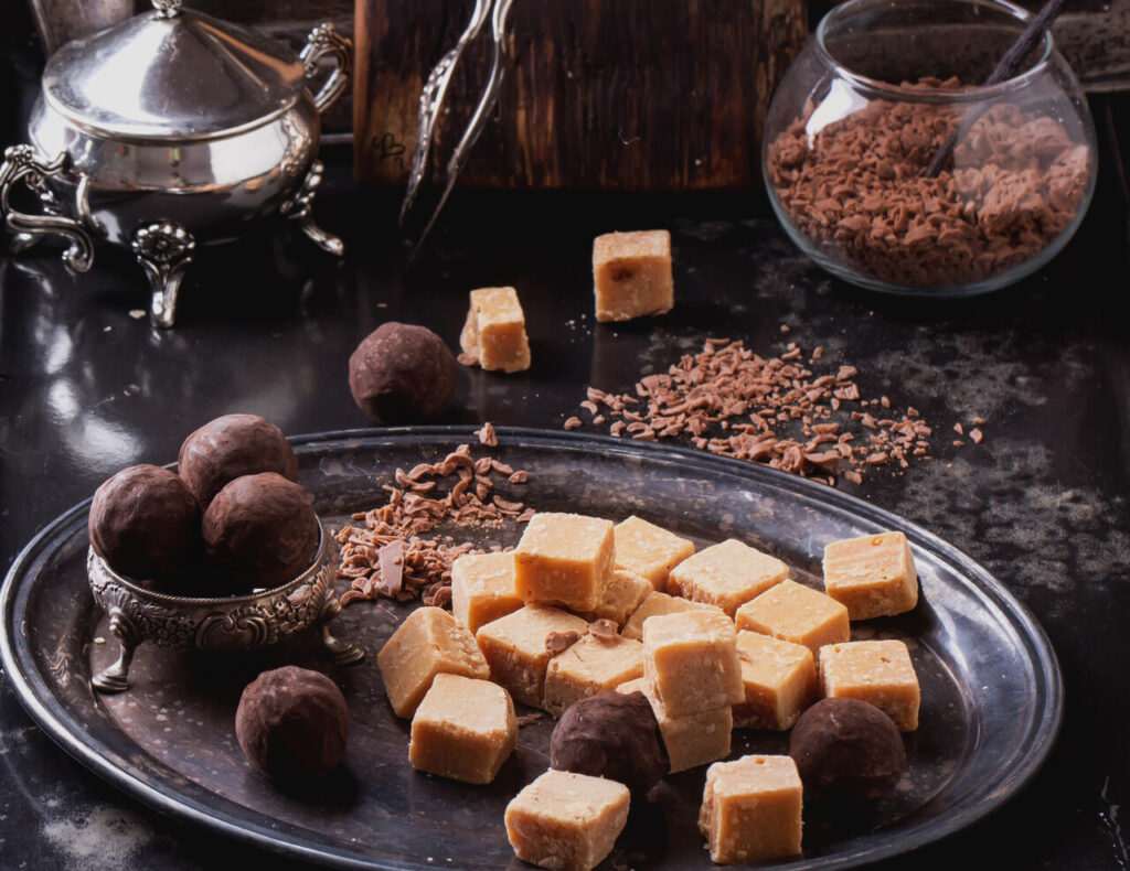 Vintage metal tray with fudge and truffle candies glass sugar bowl, served with chocolate chips