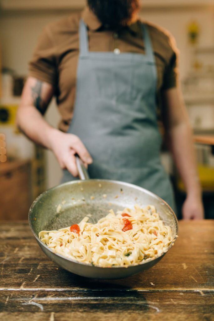 Chef mixing pasta in a bowl off the heat
