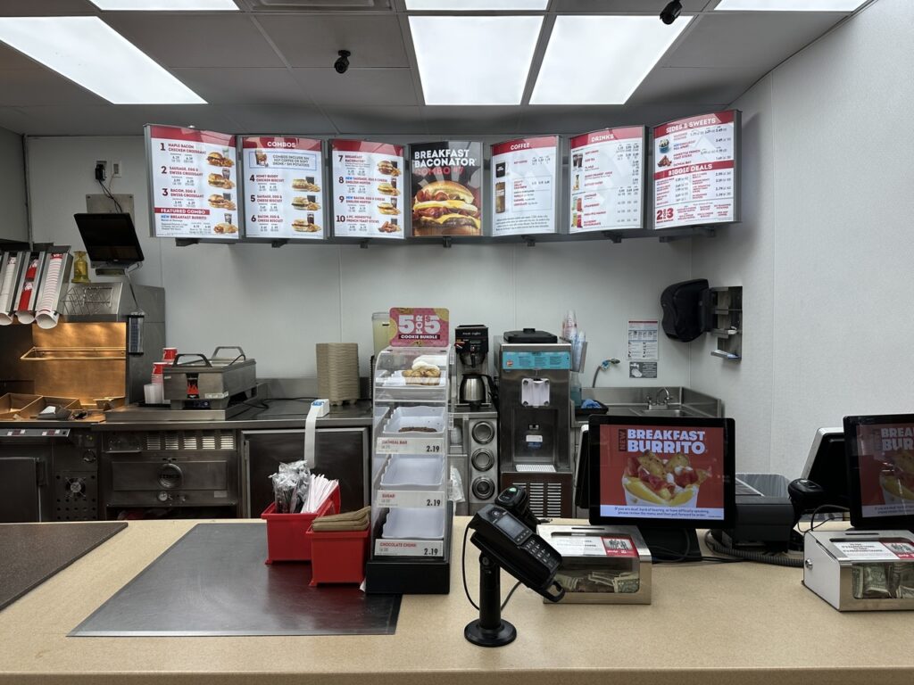 A modern, newly renovated Wendy’s interior with digital menu boards and self-order kiosks.