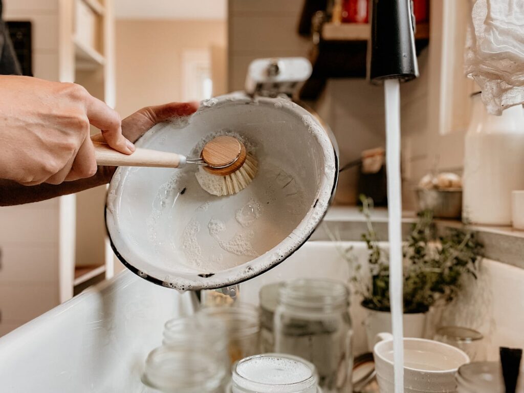 A kitchen sink with a washing-up bowl filled with soapy water beside a drying rack.