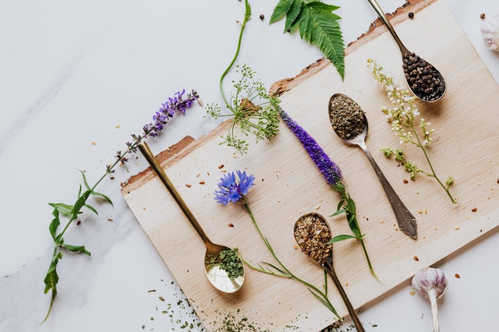 A flat-lay shot of small bowls of spices and herbs arranged on a dark wooden board.