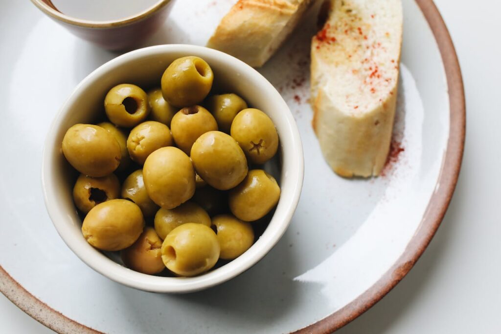 A simple wooden table with bread, olives, and water, lit by soft natural light.