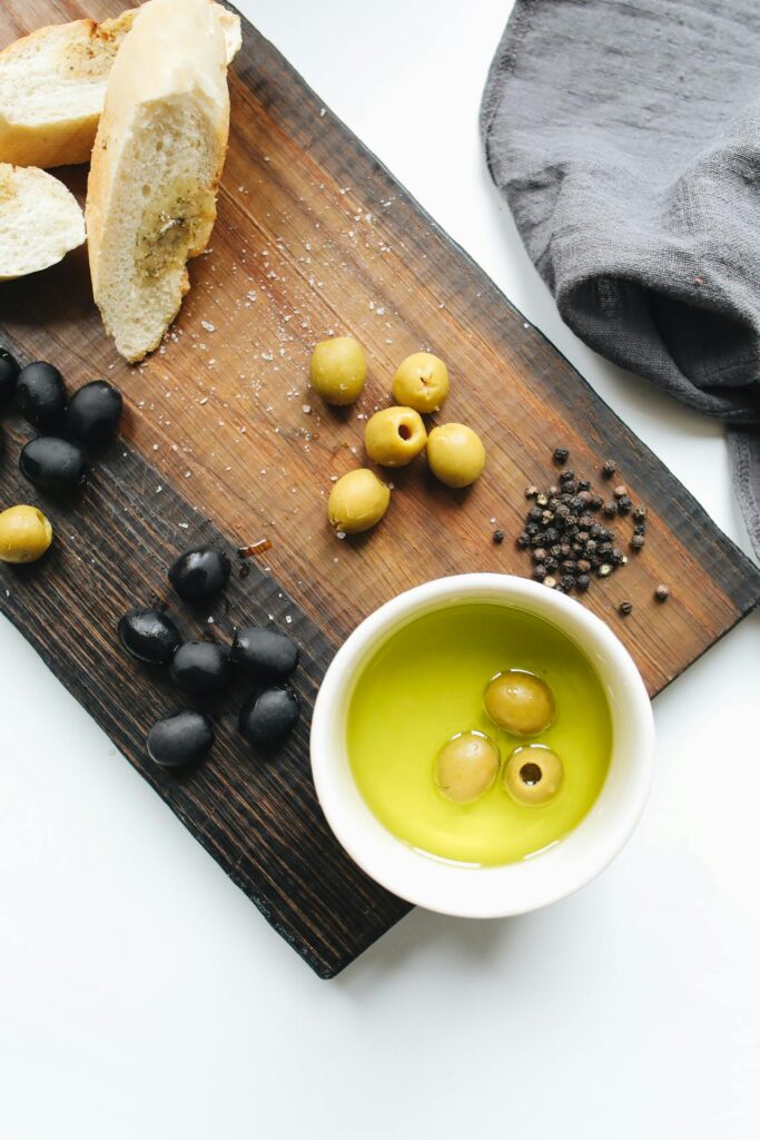 A simple wooden table with bread, olives, and water, lit by soft natural light.