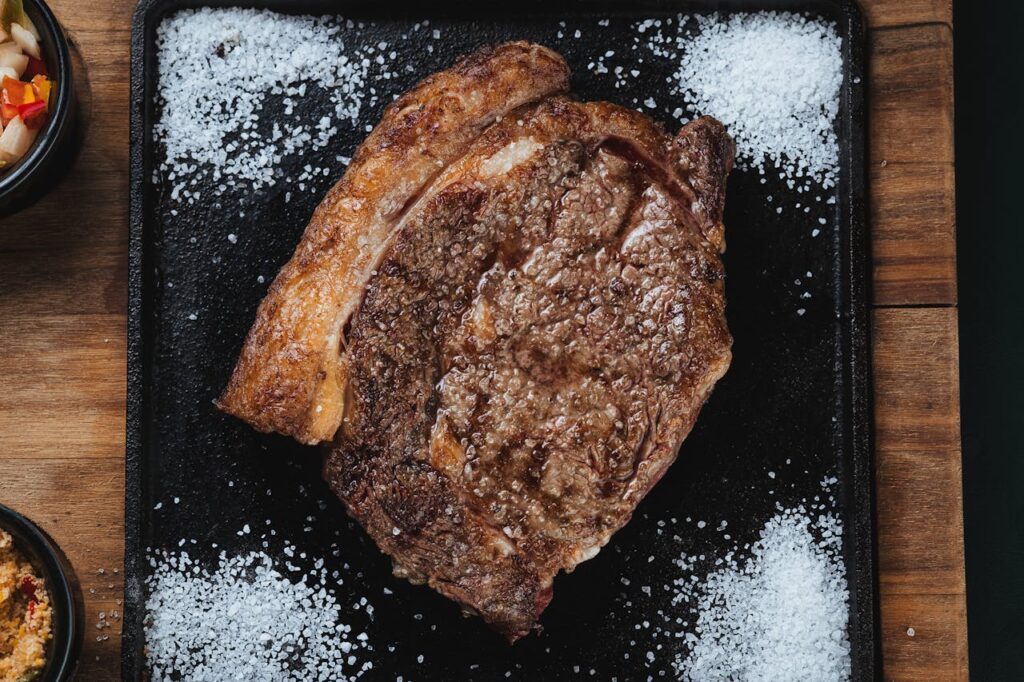 Close-up of raw ribeye on a cutting board with salt