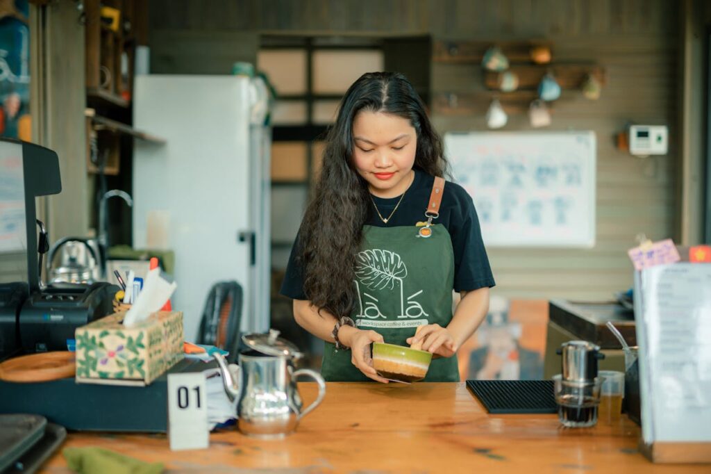 A bartender’s hands stirring coffee in a French press beside bar tools